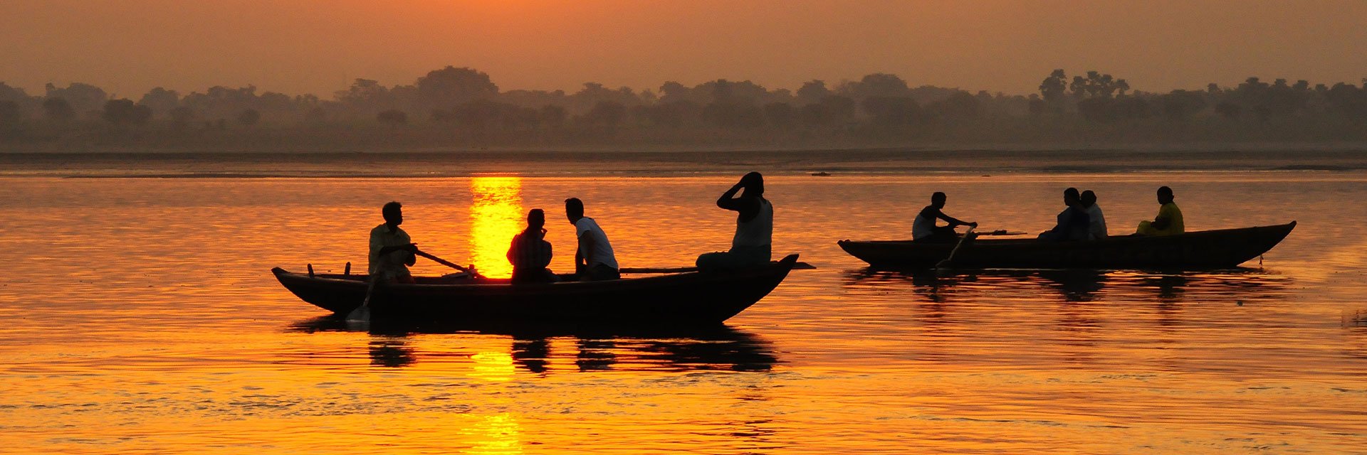 People in boats at sunset, Ganges, India.