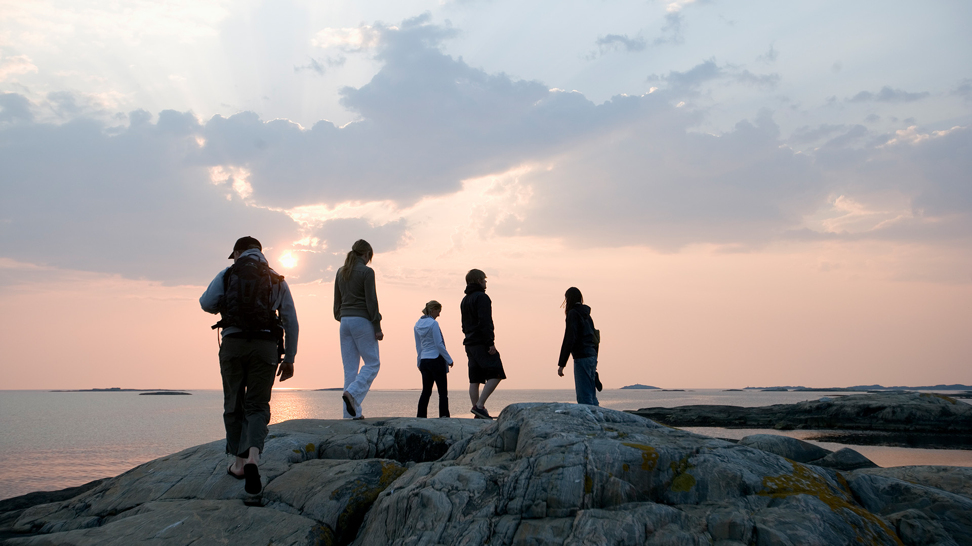 Fem personer på en klippa vid havet