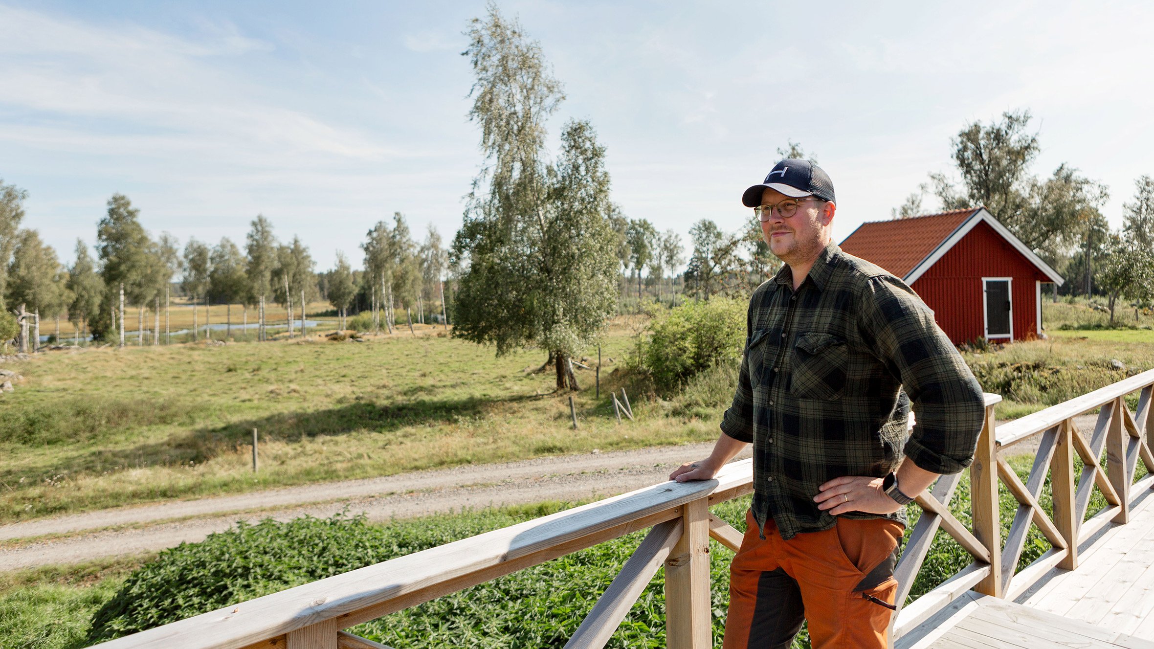 Man på trädäck som blickar ut över gård och grönska