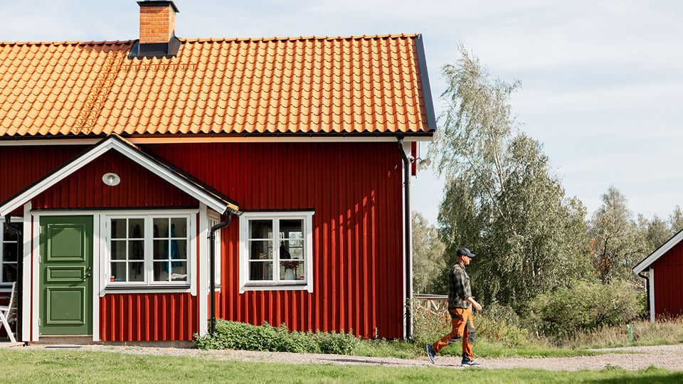 Rött hus med grön dörr och en man utanför